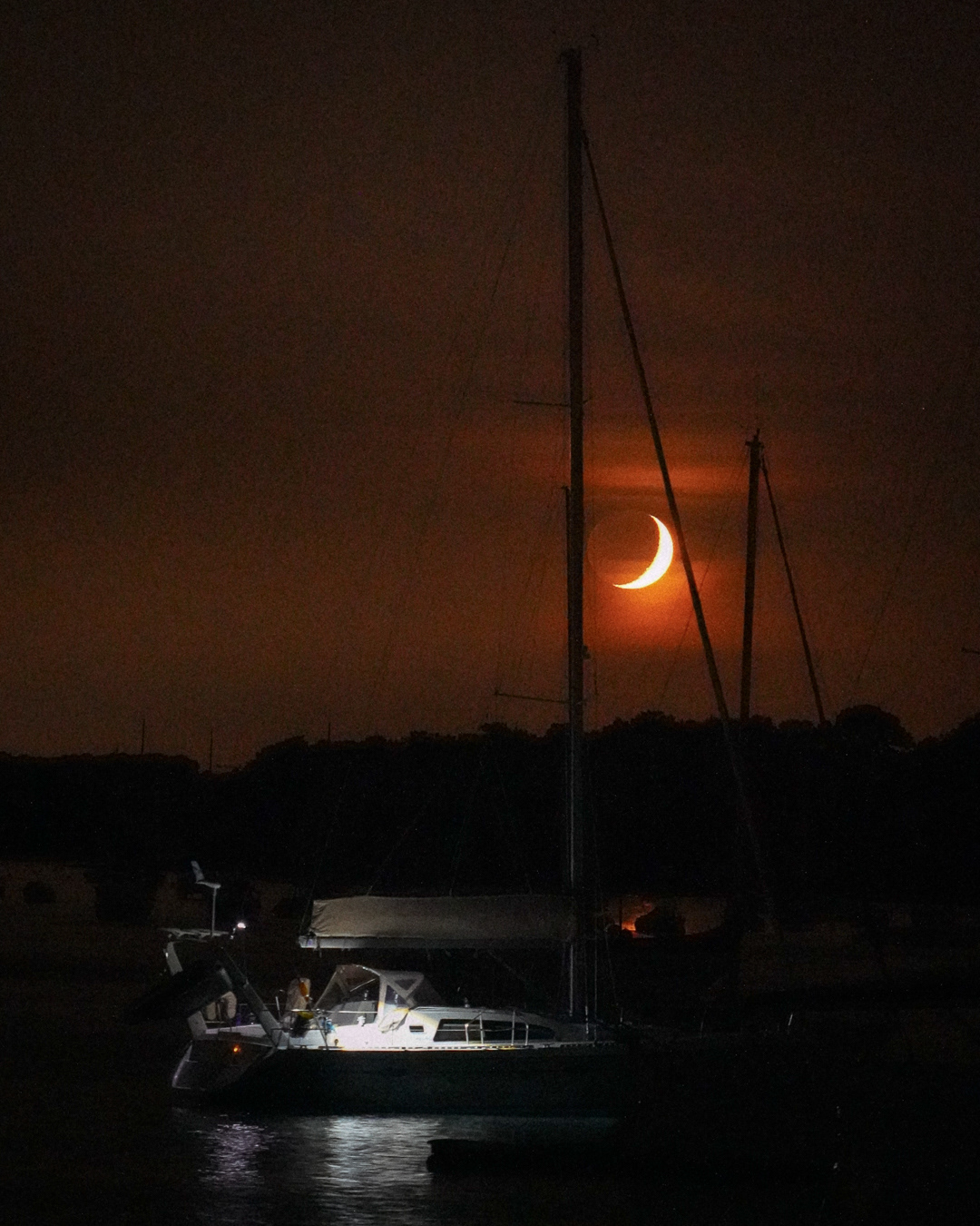 Voilier au mouillage devant une lune orange