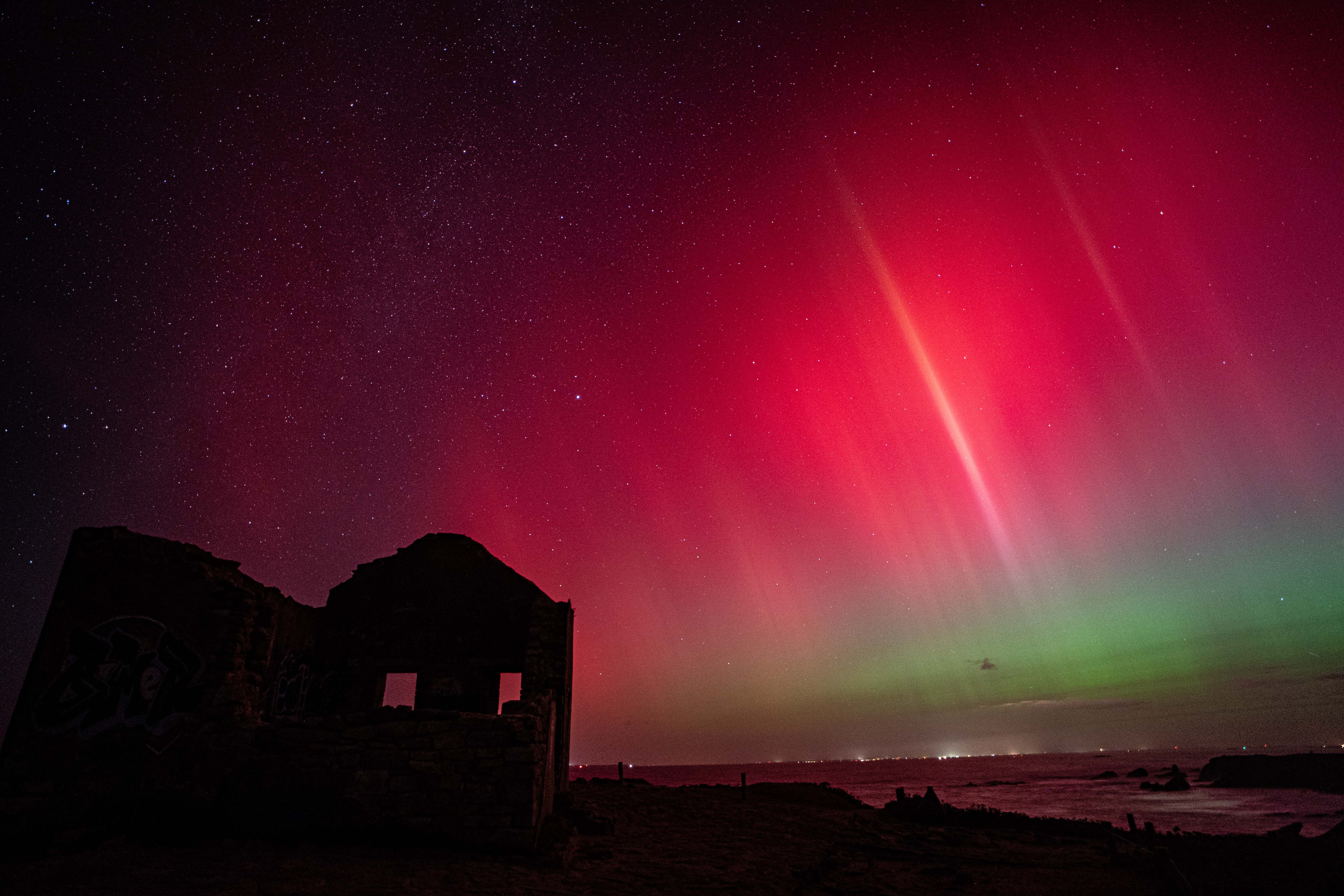 Aurore boréale rouge et verte au-dessus d’une maison