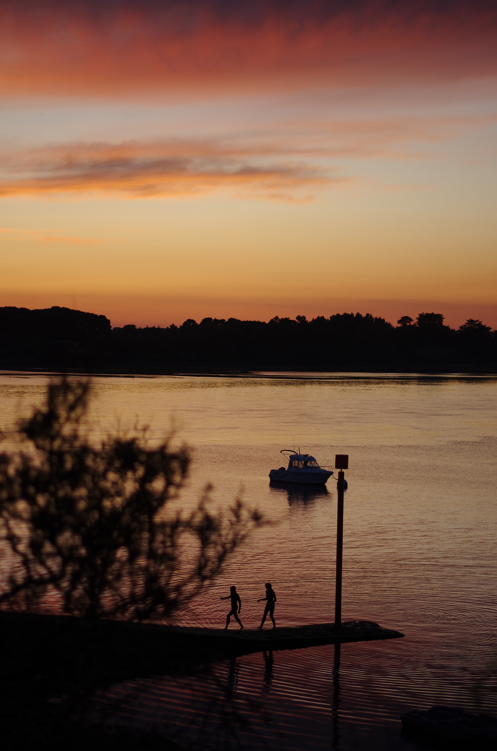 Pêcheur en silhouette sur l’eau au coucher du soleil