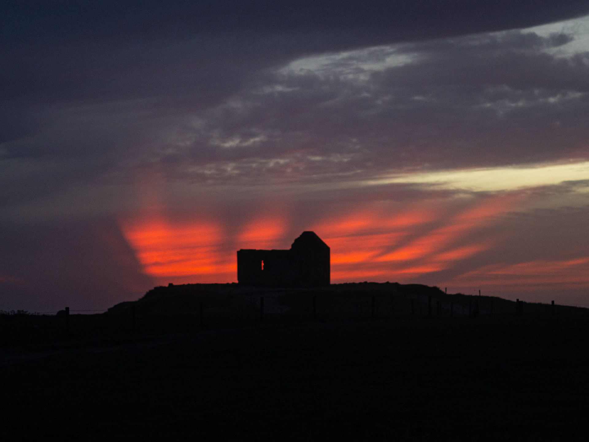 Maison en silhouette sous un ciel rouge après le coucher du soleil